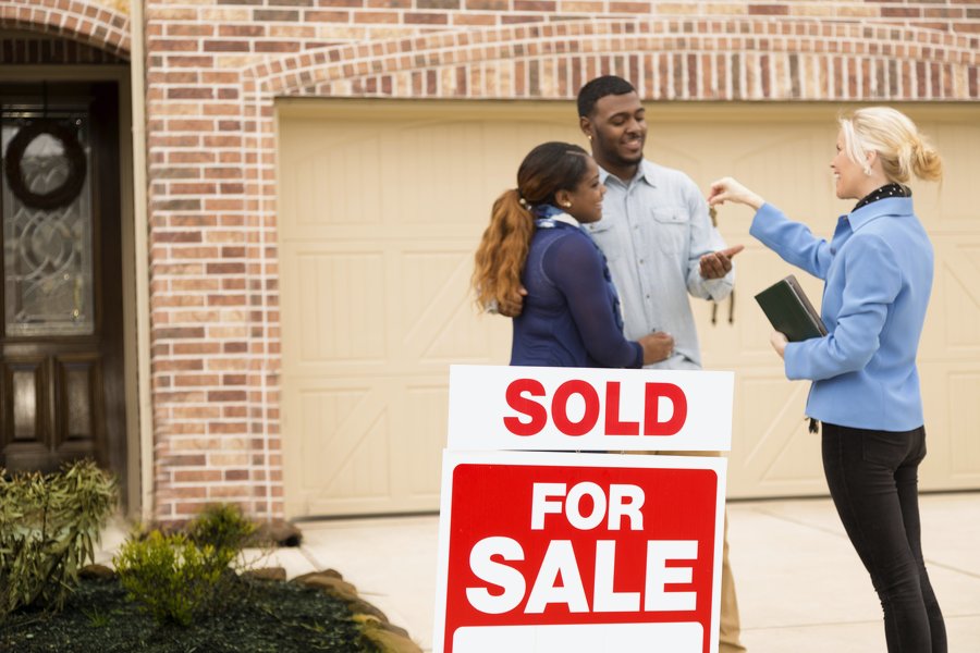 Real estate agent handing over keys to clients, representing legal, financial, and professional services
